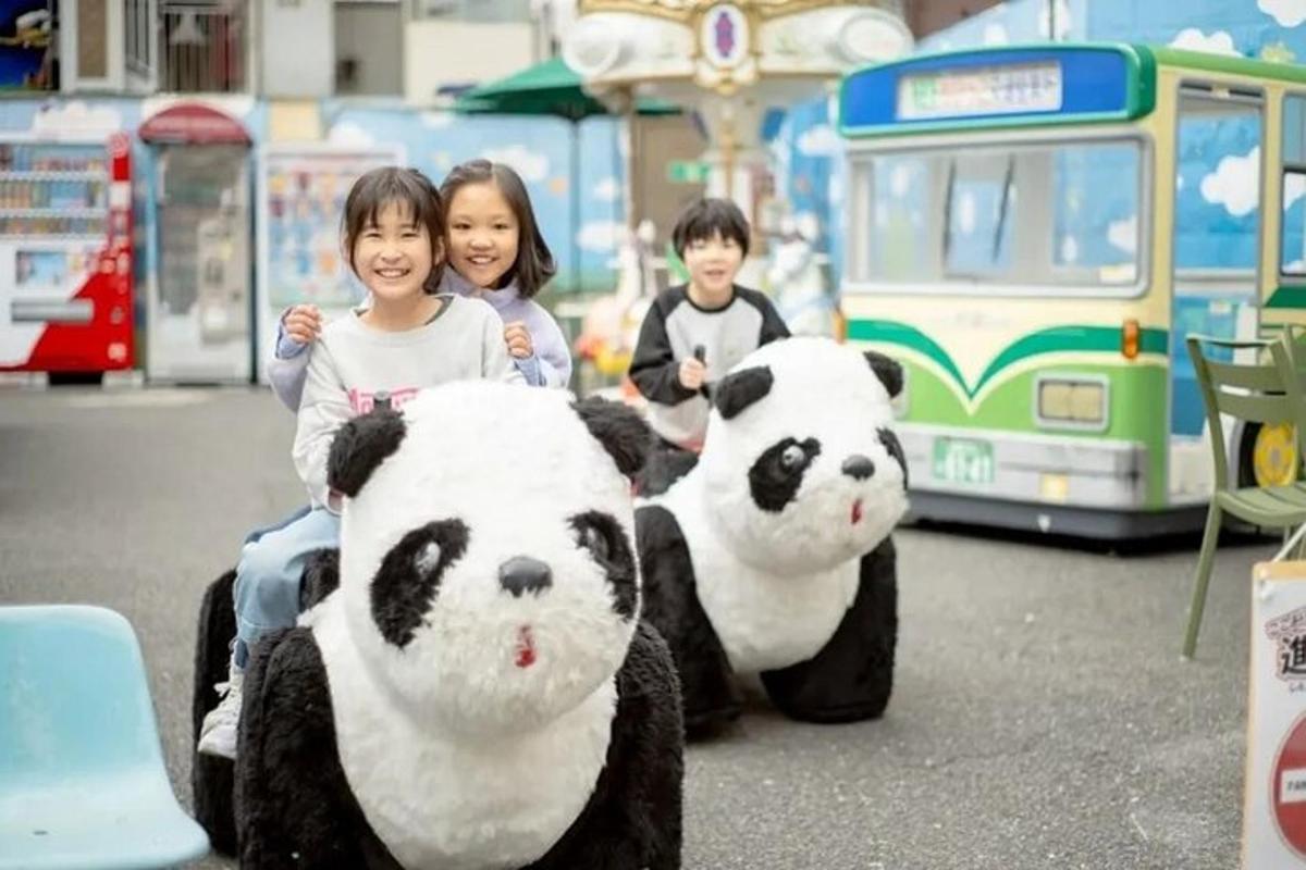 two children are standing next to two giant panda bears