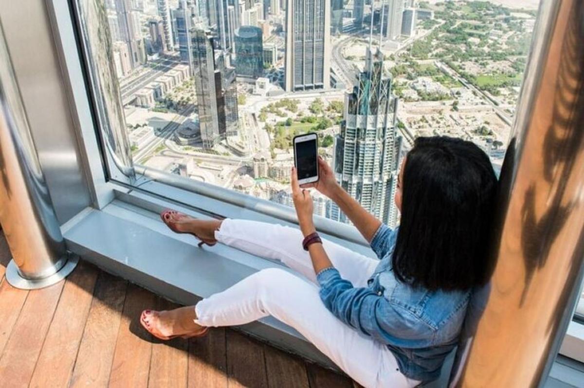 a woman sitting on a window ledge holding a cell phone