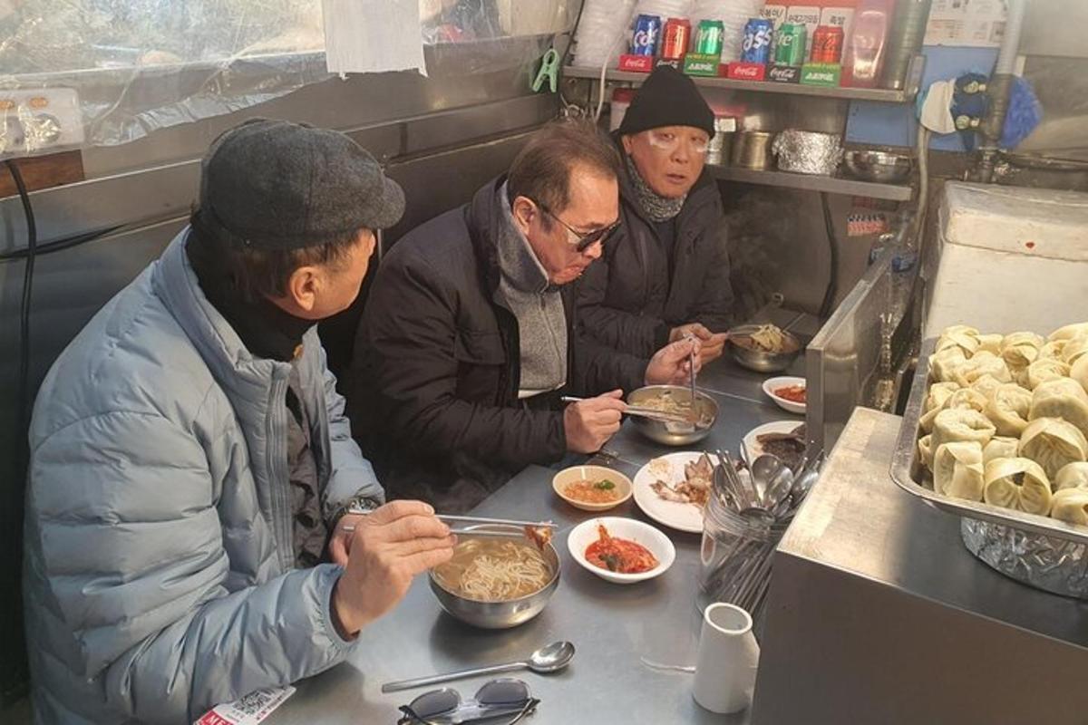 un gruppo di uomini seduti a un bancone che mangiano cibo