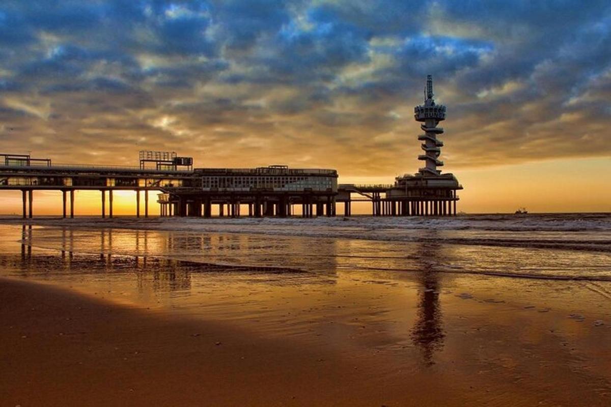 une jetée avec un phare sur la plage au coucher du soleil