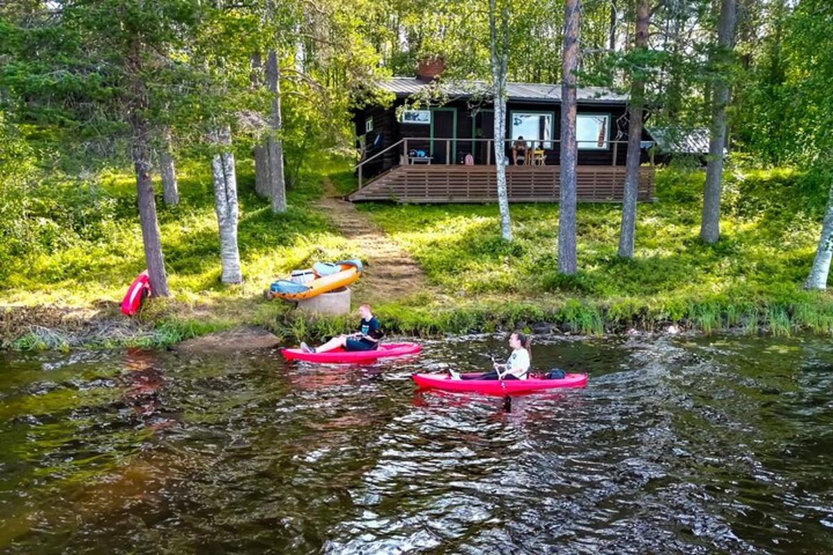 two people on kayaks in the water in front of a cabin