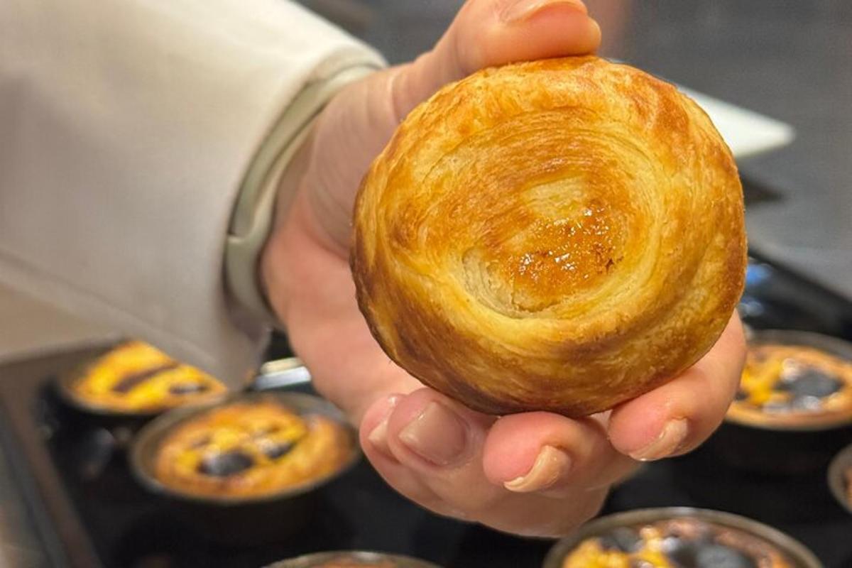 a person holding a pastry in front of muffins