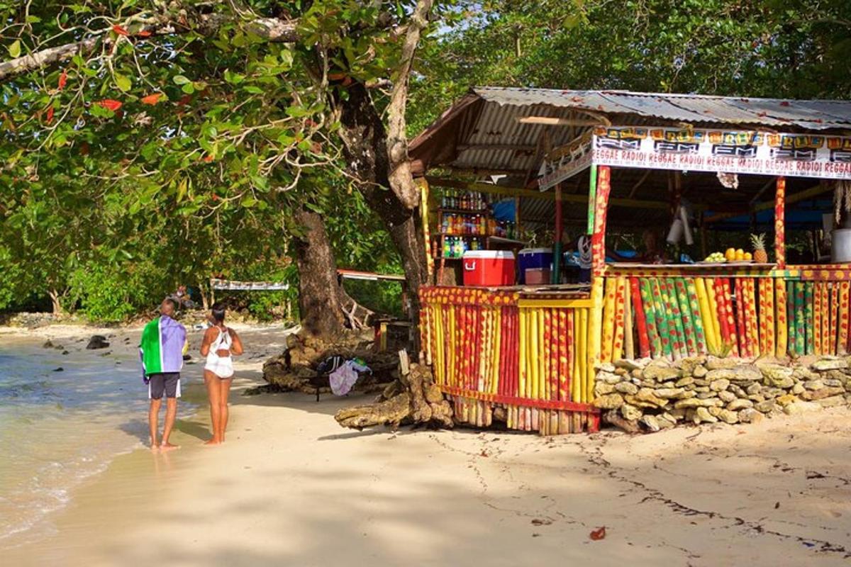 two people walking on a beach next to a shop