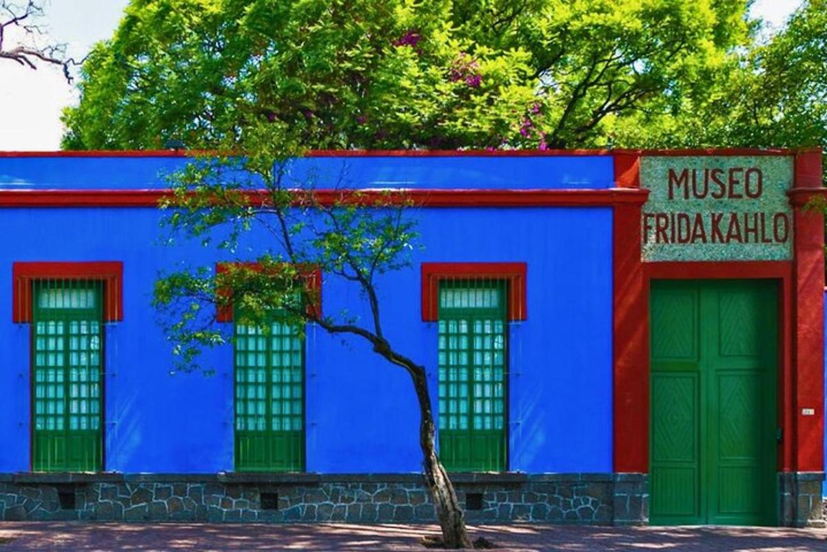 a blue building with three windows and a tree in front