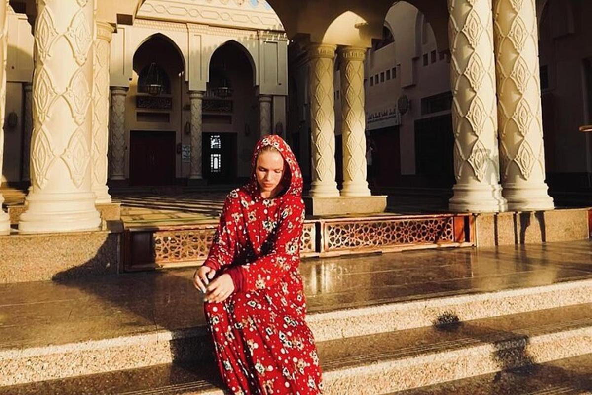 seorang wanita berpakaian merah berdiri di hadapan sebuah bangunan