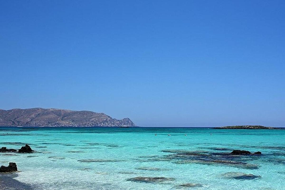 Una playa con agua azul y montañas al fondo.