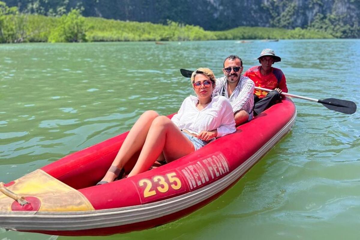 tři lidé sedící v červené lodi na vodě