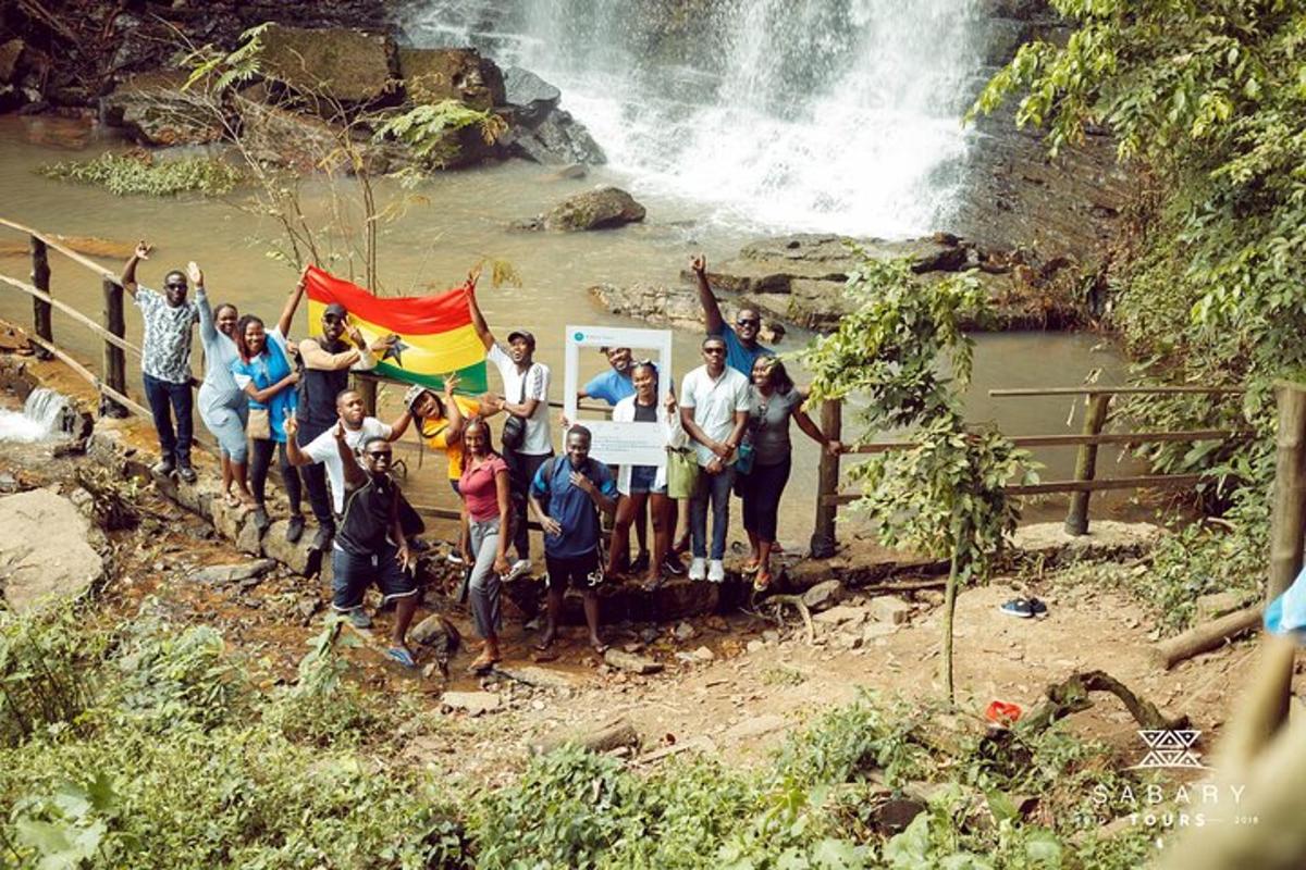 um grupo de pessoas em pé em frente a uma cachoeira