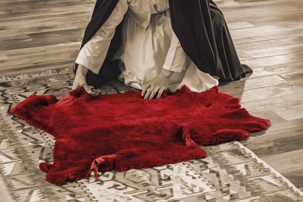 Una mujer está sentada sobre una alfombra roja en el suelo.