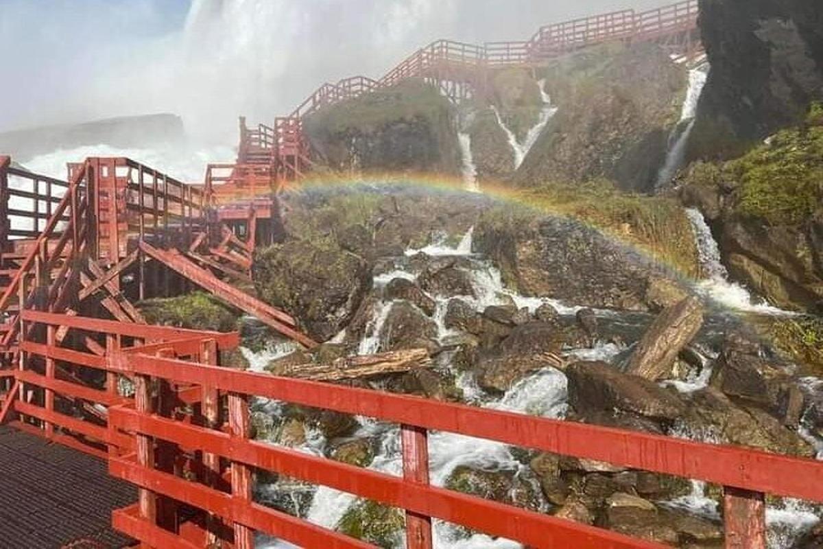 a rainbow over a waterfall and a bridge