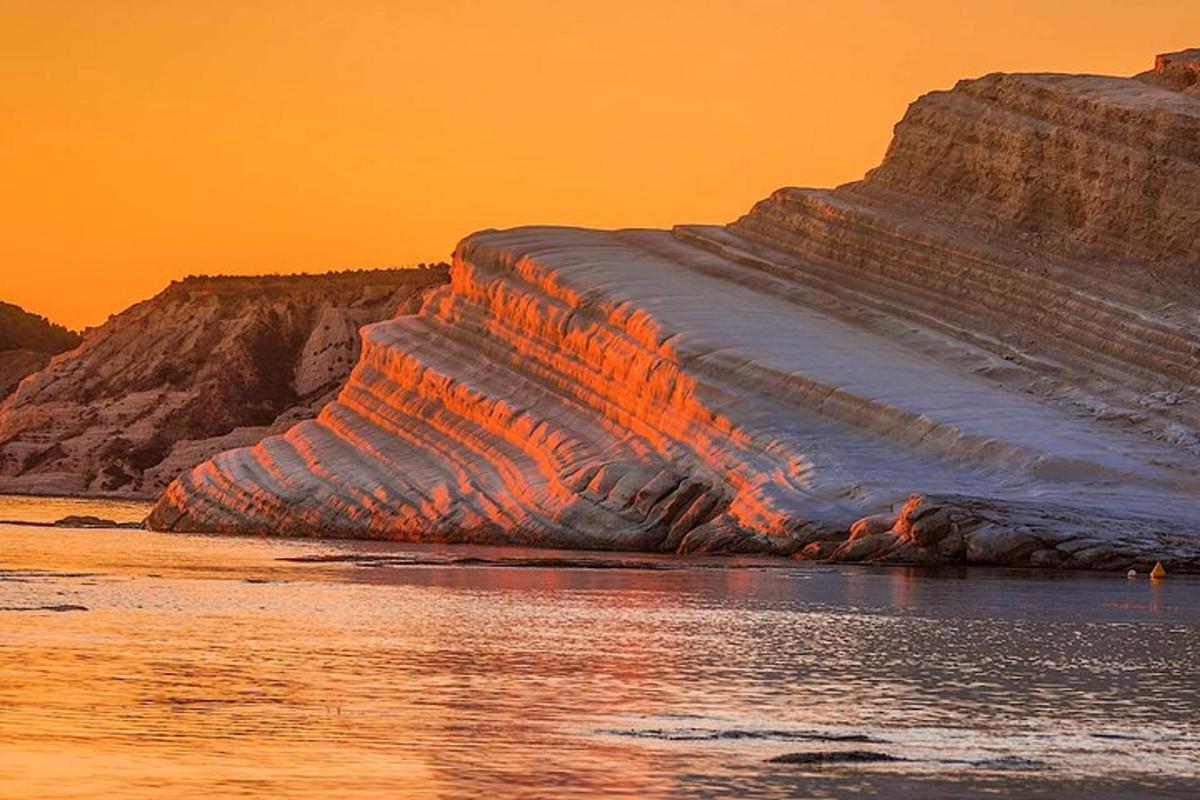 un iceberg nell'acqua con un tramonto sullo sfondo