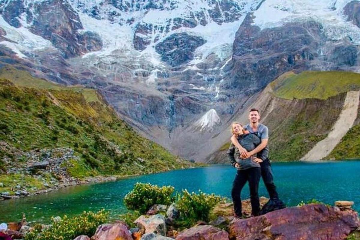 Un hombre y una mujer de pie sobre una roca junto a un lago