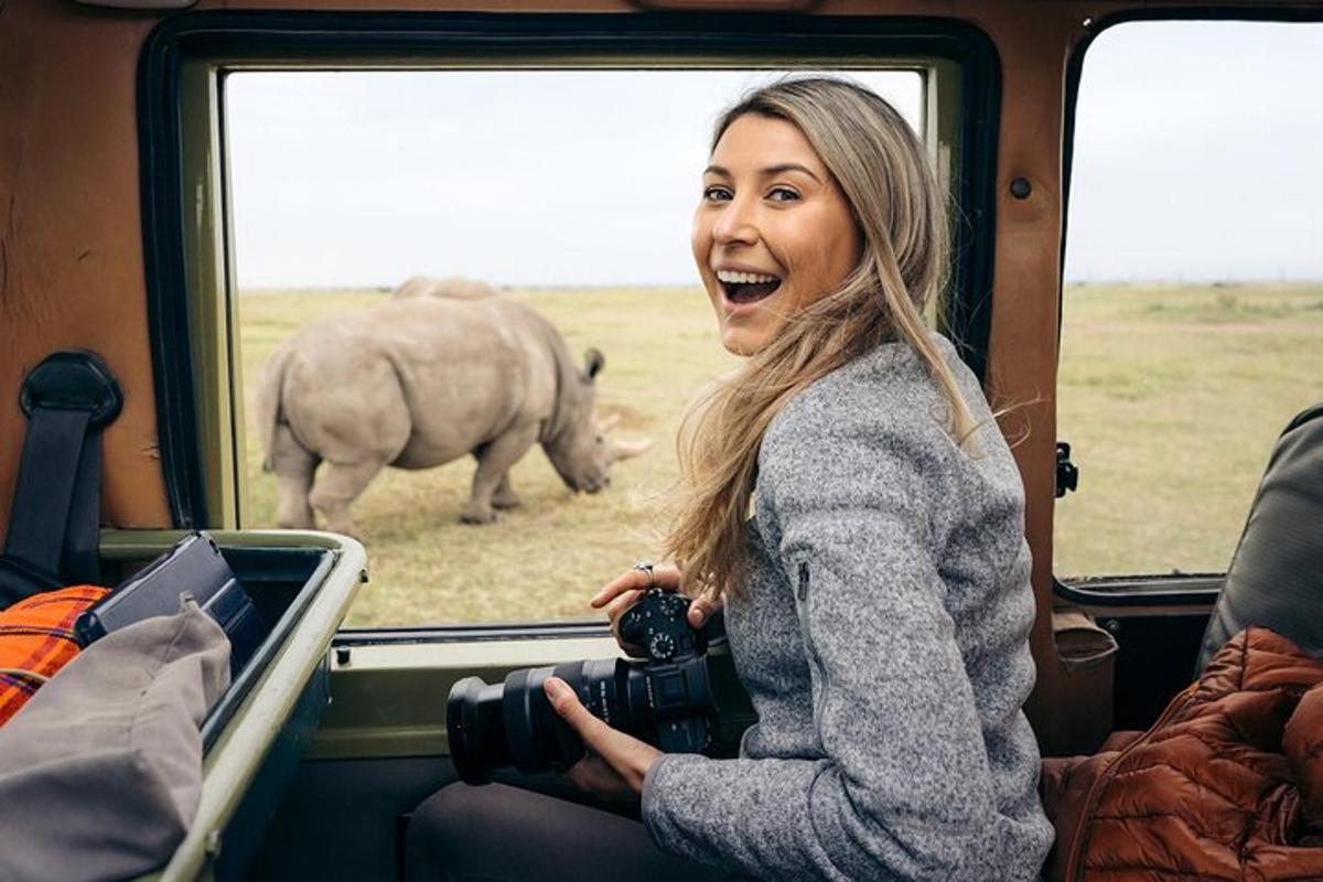 eine Frau mit einer Kamera in einem Zug, die ein Nashorn beobachtet