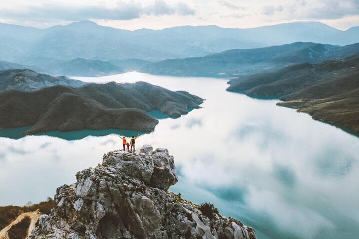 dva lidé stojící na vrcholu hory s výhledem na jezero