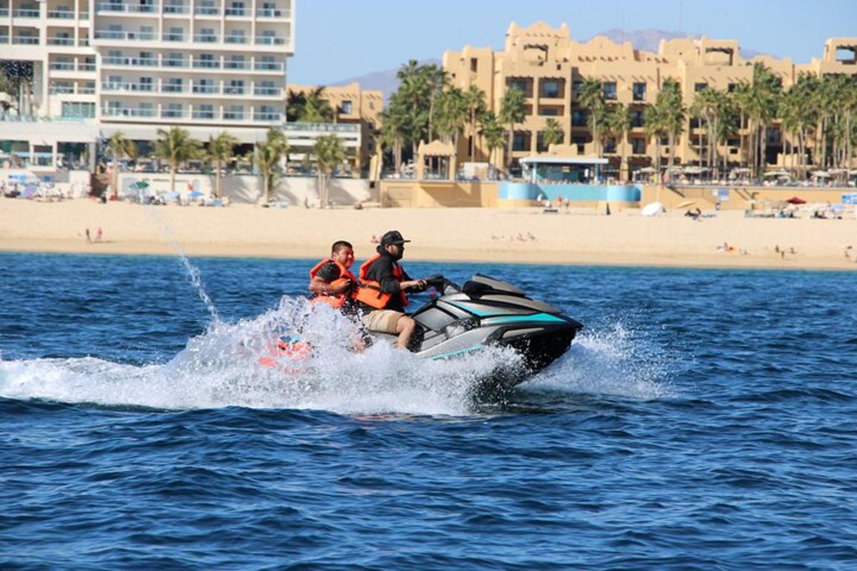 dua orang menaiki jet ski di dalam air berhampiran pantai