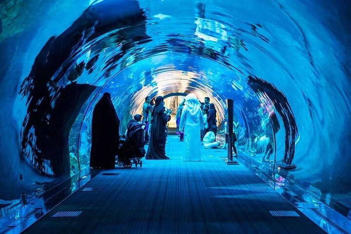 a group of people walking through a tunnel with an aquarium