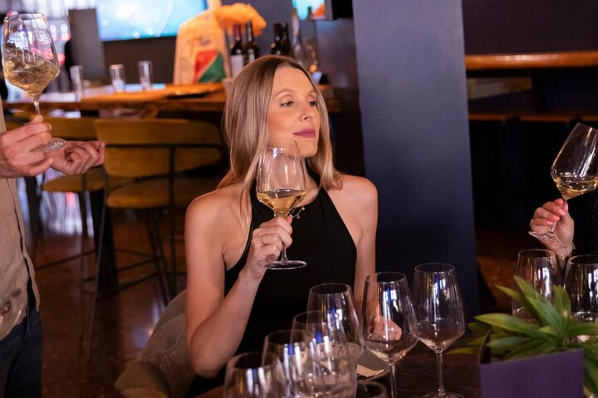 žena sedící u stolu a držící sklenici vína