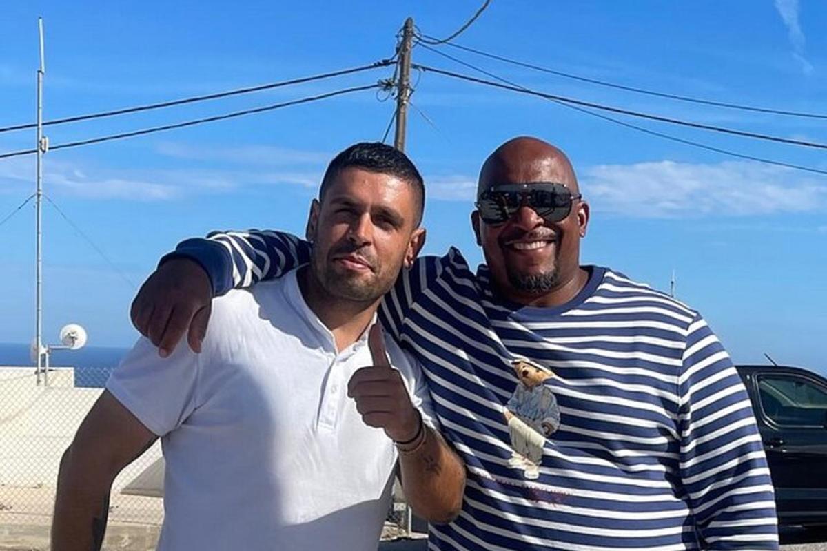 dois homens parados um ao lado do outro fazendo sinal de positivo