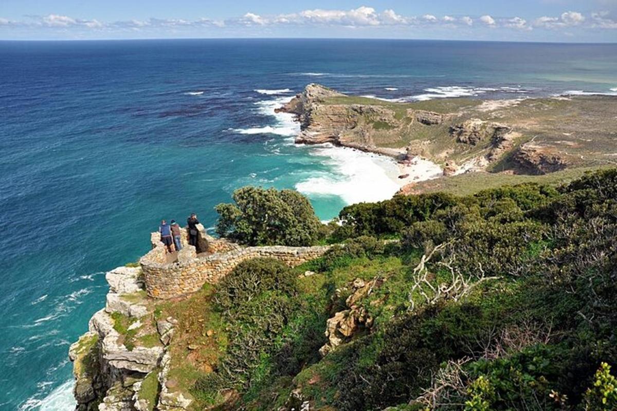 un grup de persones dretes en un penya-segat amb vistes a l'oceà