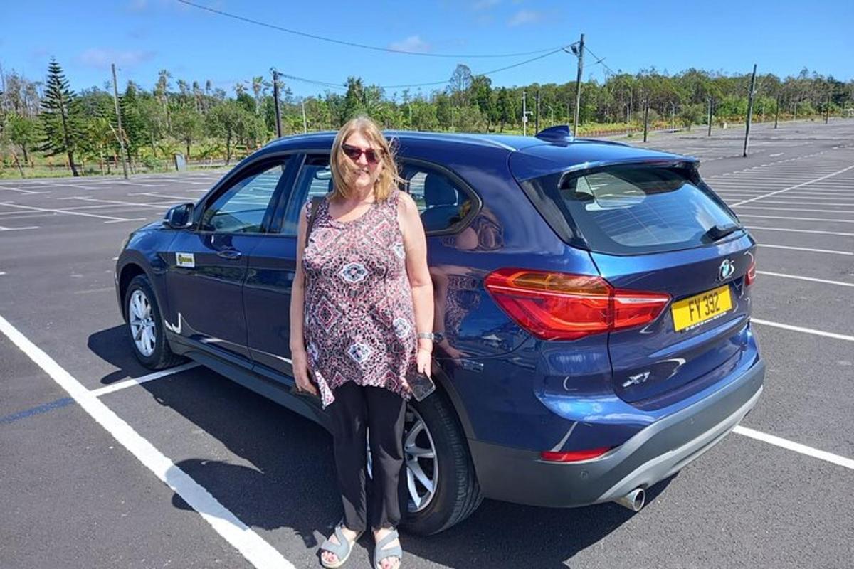 uma mulher parada ao lado de um carro azul em um estacionamento