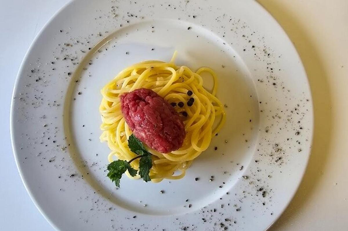 en tallerken med pasta med et stykke kjøtt på