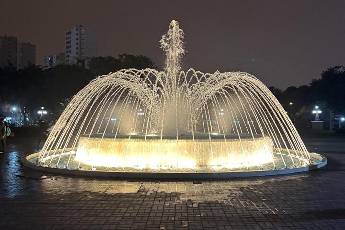 Una fuente con luces en una ciudad por la noche.
