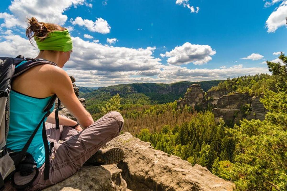 eine Frau, die auf einem Felsen sitzt und über die Schlucht blickt