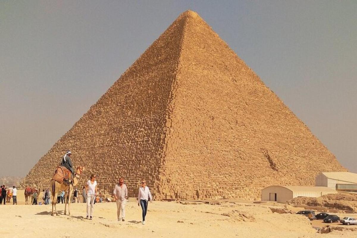 skupina lidí kráčejících před pyramidou
