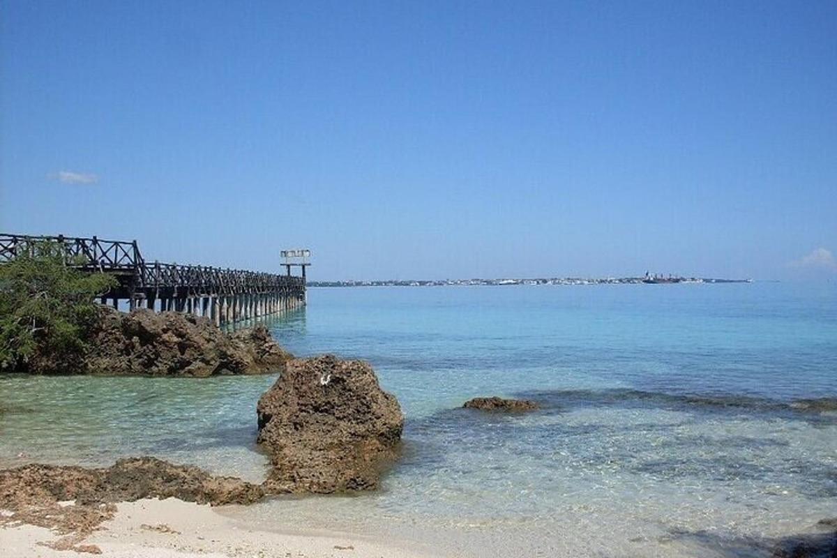 ein Strand mit einem Felsen im Wasser und einem Pier