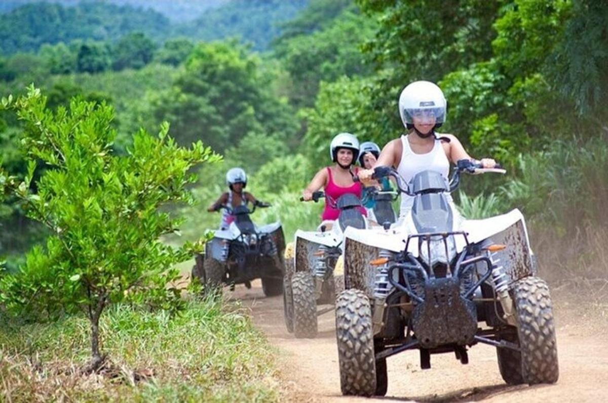 three people riding on atvs on a dirt road