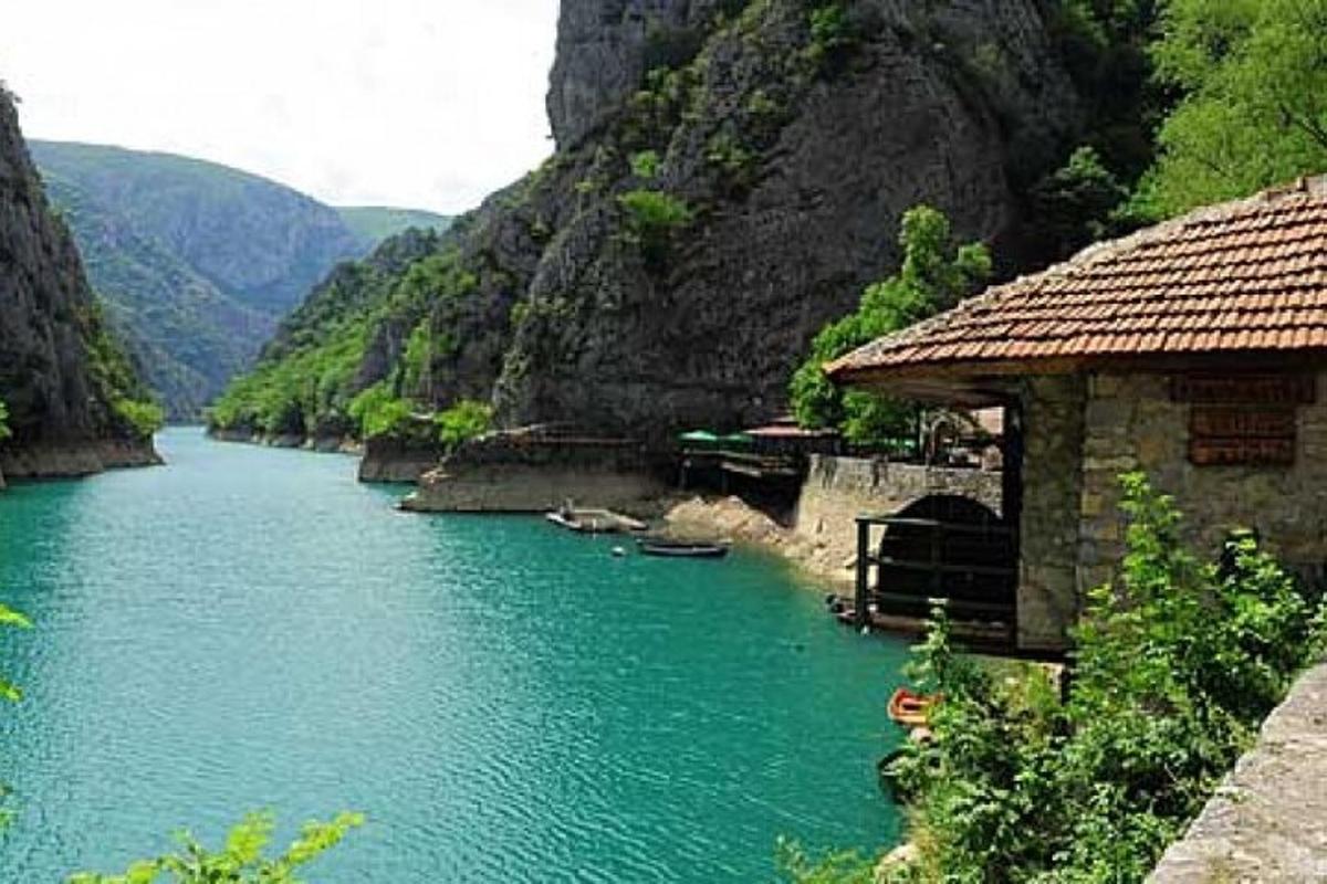a river with a building on the side of a mountain