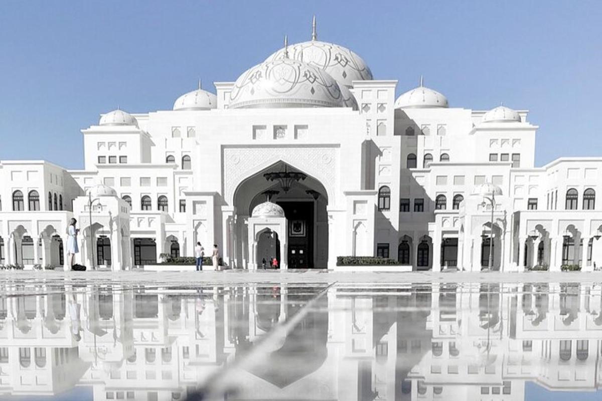 a large white building with its reflection in the water