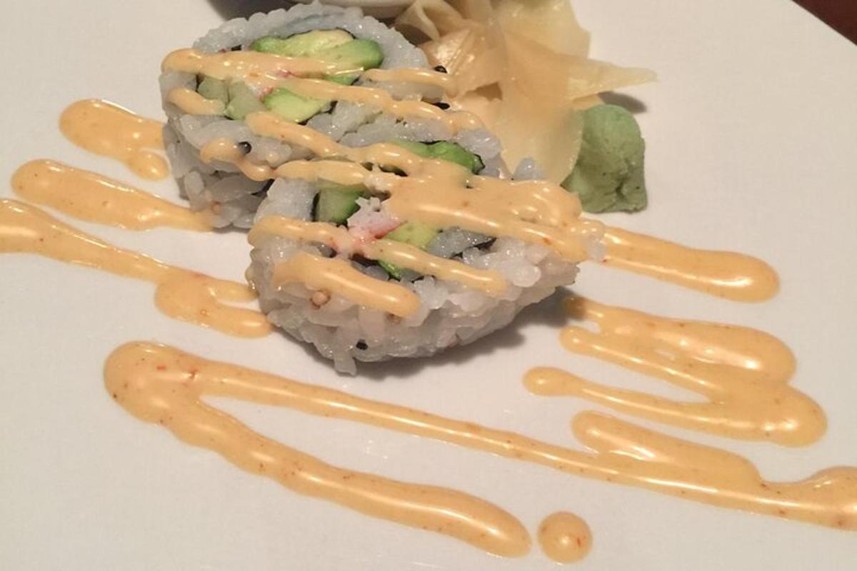 kousek sushi s omáčkou na bílém talíři