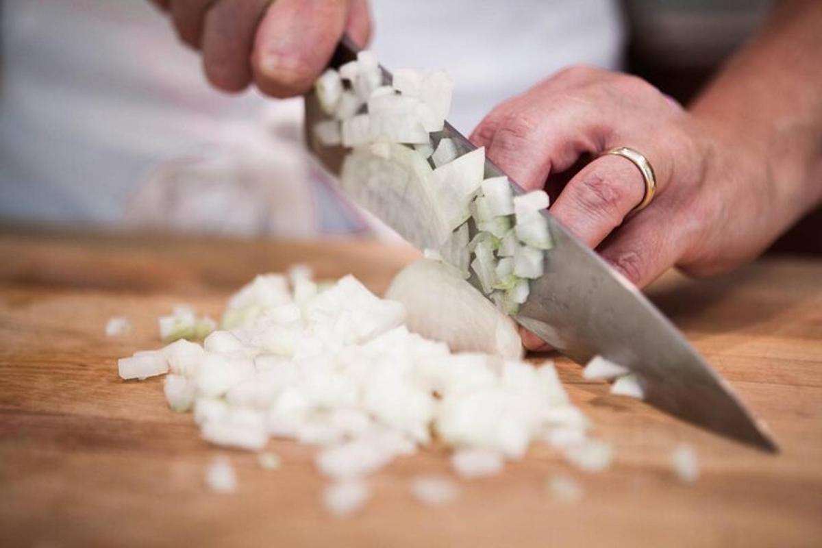 una persona cortando cebollas en una tabla de cortar con un cuchillo