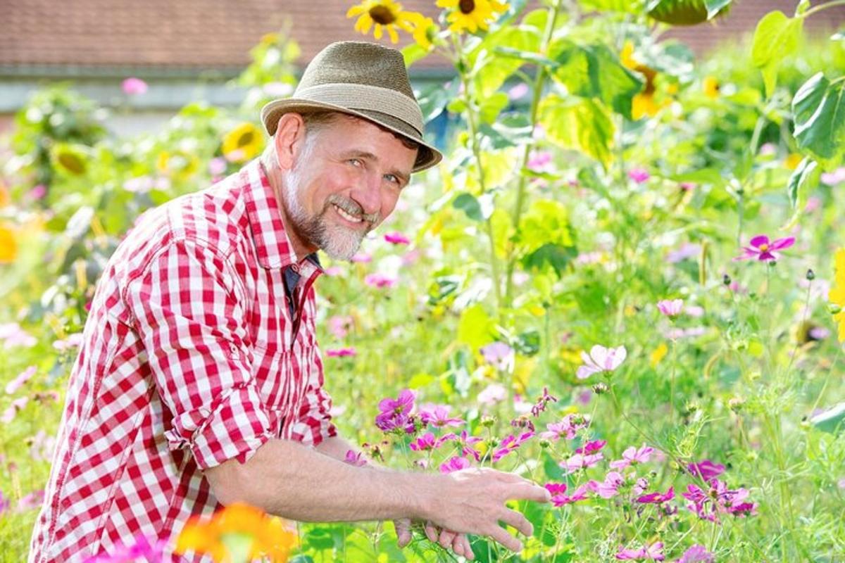 Un hombre con sombrero en un jardín con flores.