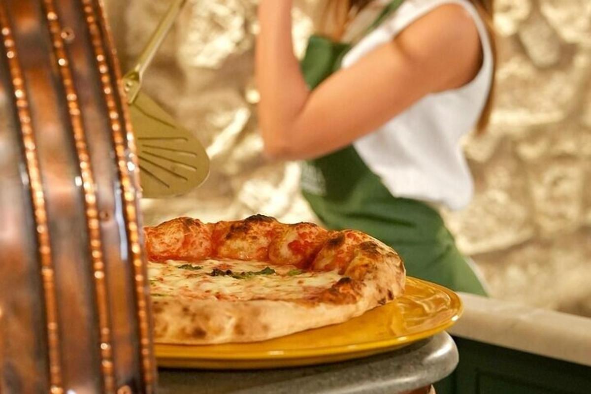 Žena stojí vedľa taniera s pizzou