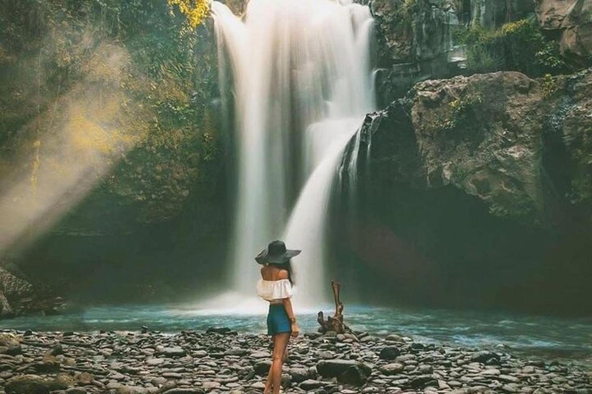 seorang wanita berdiri di hadapan air terjun