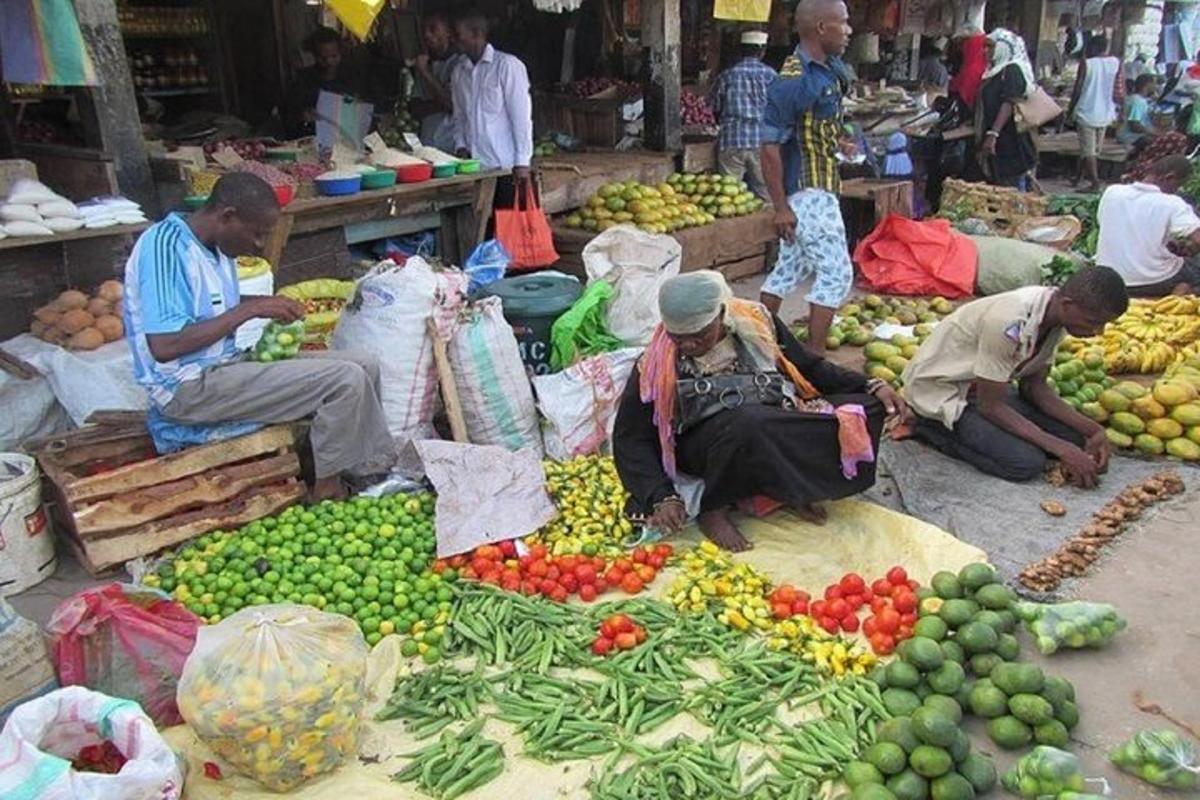 Un grupo de personas en un mercado con frutas y verduras.