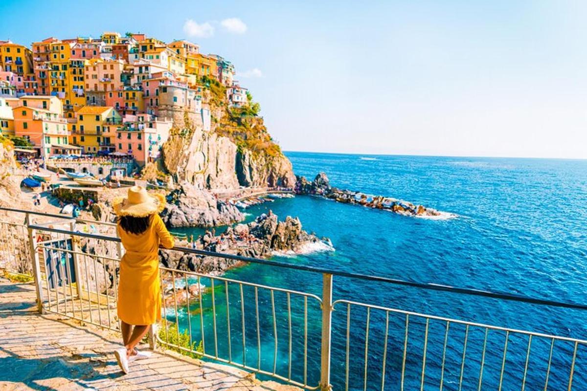 una donna in un vestito giallo in piedi su un balcone che guarda l'oceano
