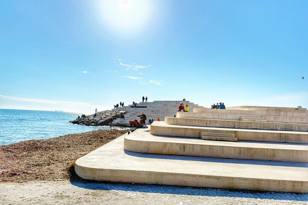 a group of people sitting on steps next to the ocean
