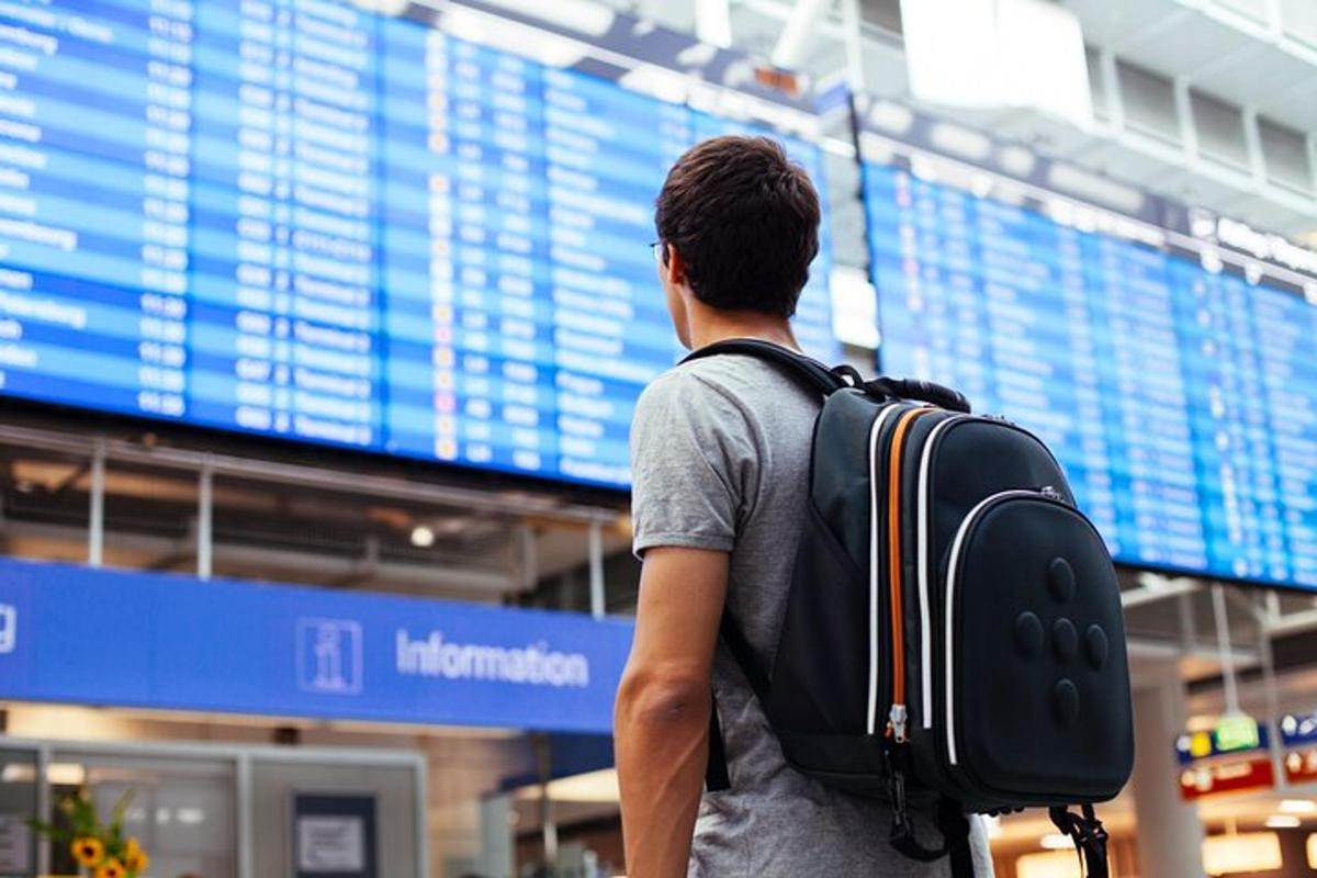 um homem com uma mochila em pé em frente a um aeroporto