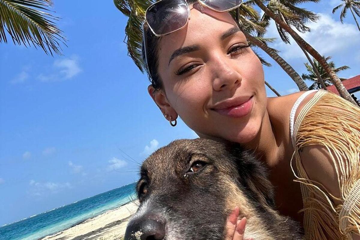 una donna in piedi accanto a un cane sulla spiaggia