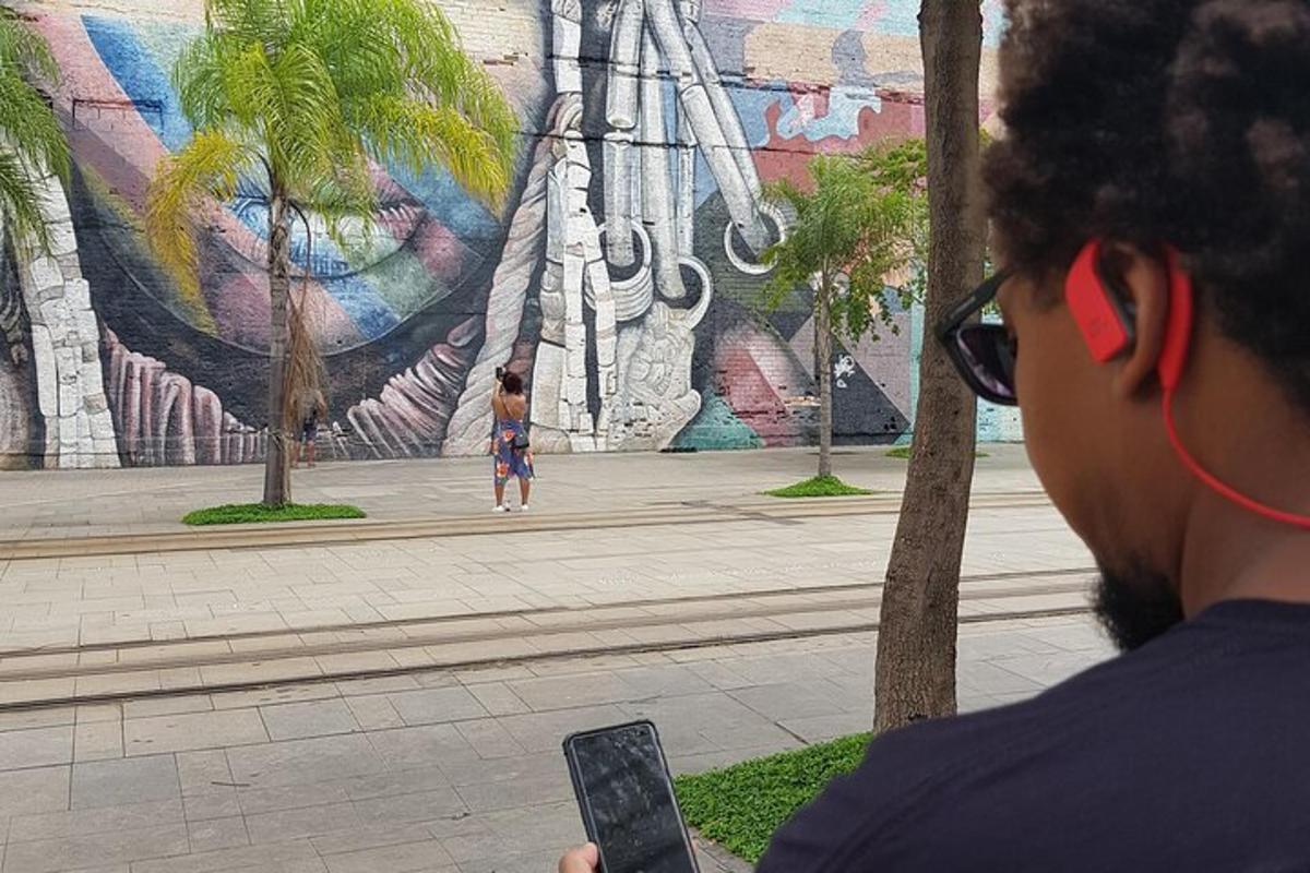 uma pessoa segurando um celular em frente a um mural