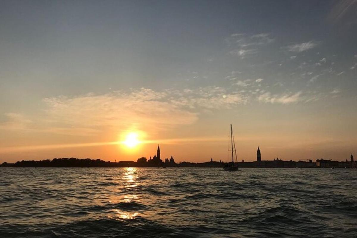 una posta de sol sobre una massa d'aigua amb un vaixell