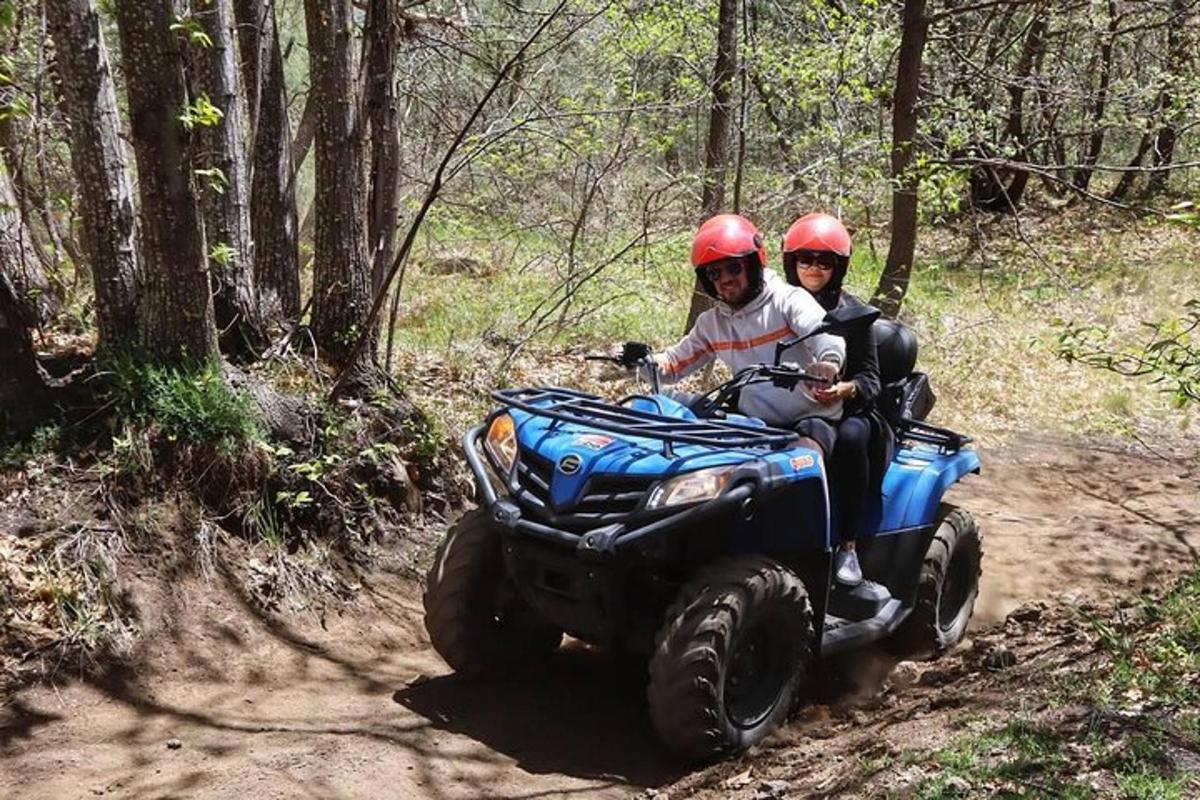 two people riding on a four wheeler on a trail