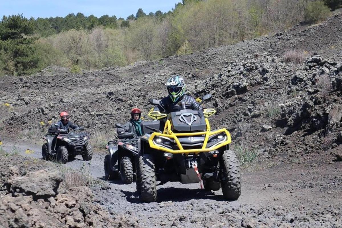 two people riding on atvs on a dirt road