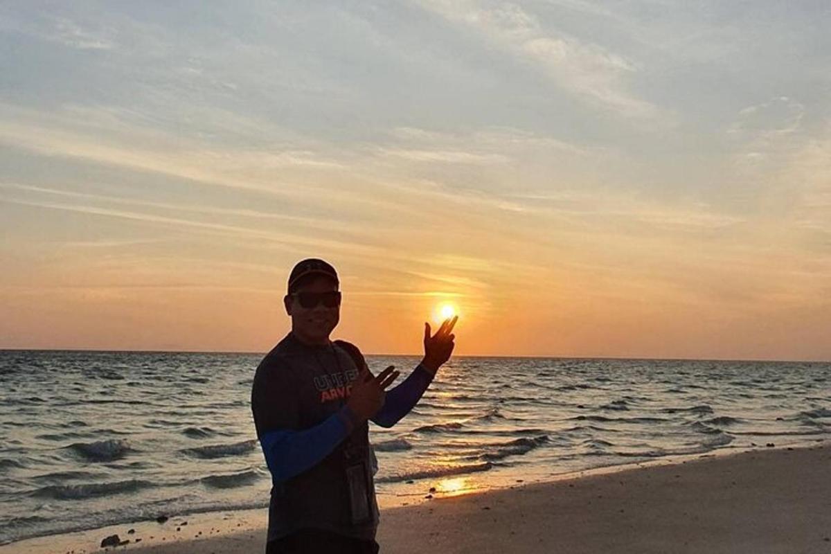 一名男子站在海滩上，背景是日落