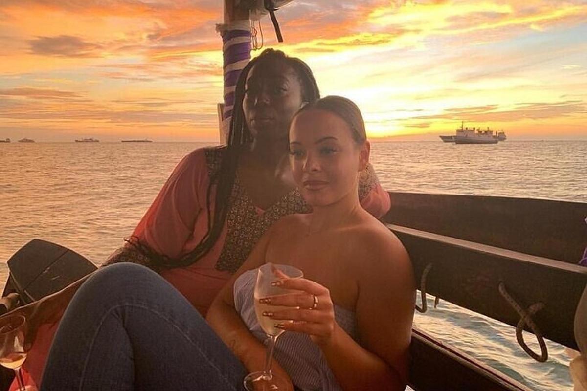 two women sitting on a boat with a wine glass