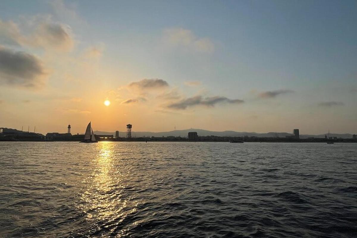 una barca a vela sull'acqua mentre il sole tramonta