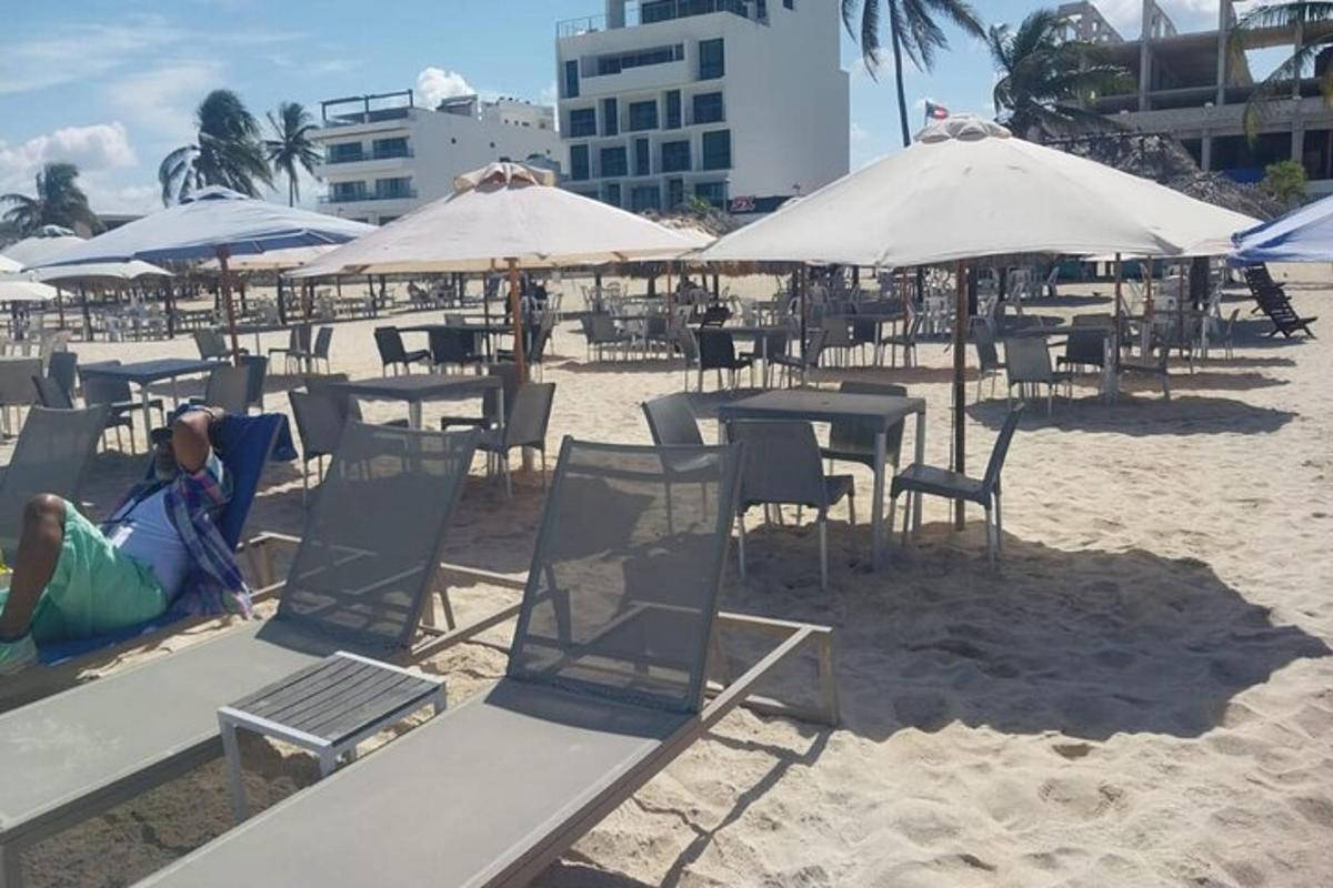 una persona tumbada en la playa con sillas y sombrillas